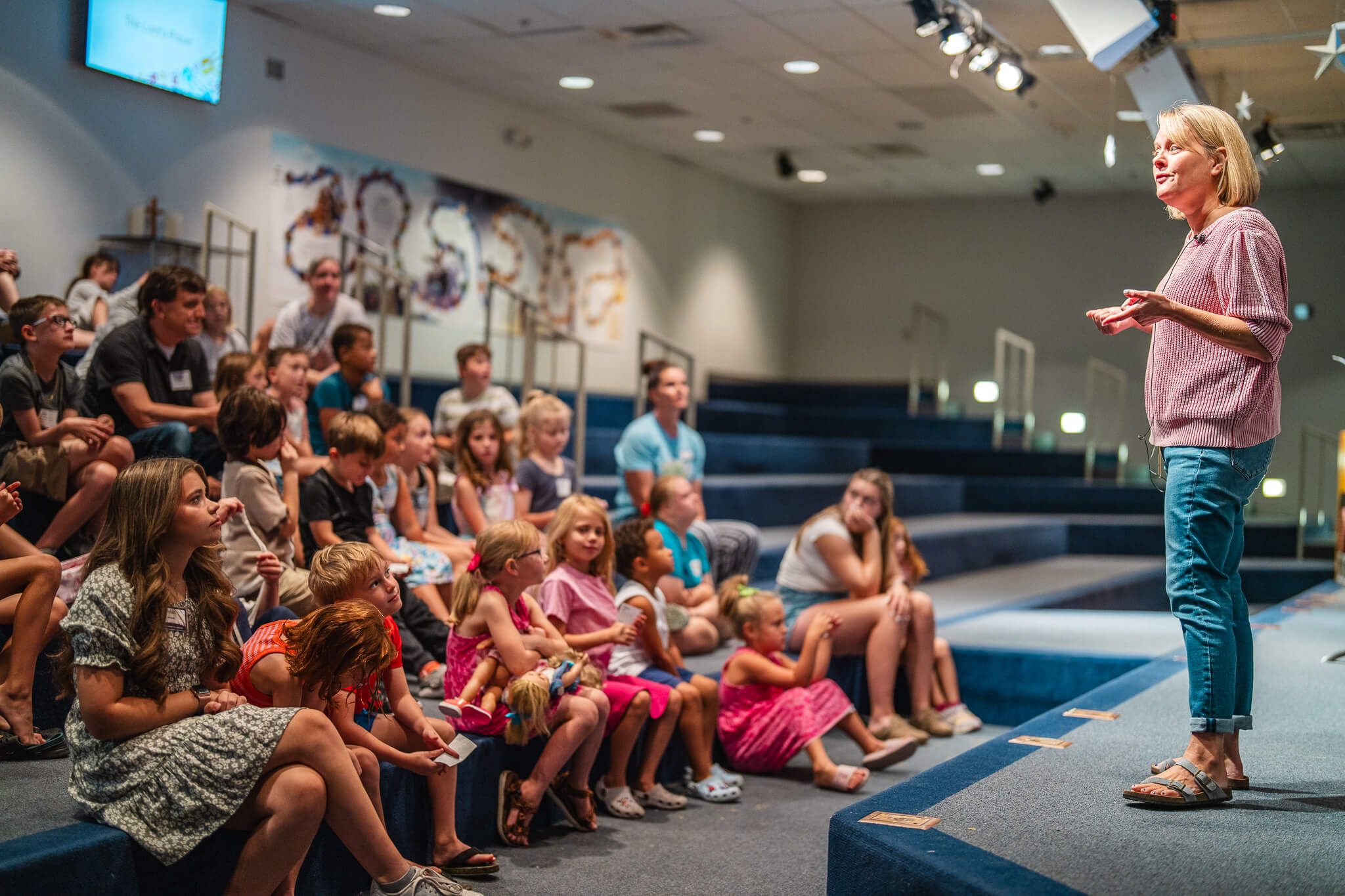 Children learn in a large group setting about Jesus.